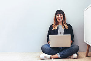 eine Frau, die mit ihrem Laptop auf dem Boden sitzt
