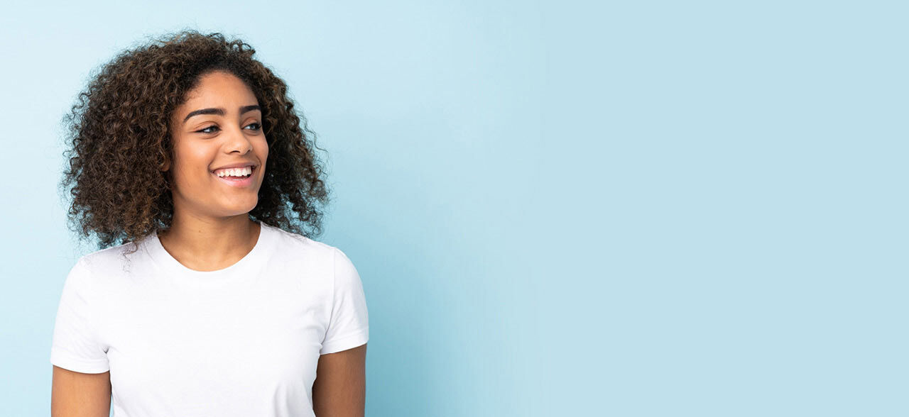 eine Frau mit lockigen Haaren lächelnd und nach oben