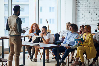 eine Gruppe von Menschen, die an Schreibtischen in einem Zimmer sitzen