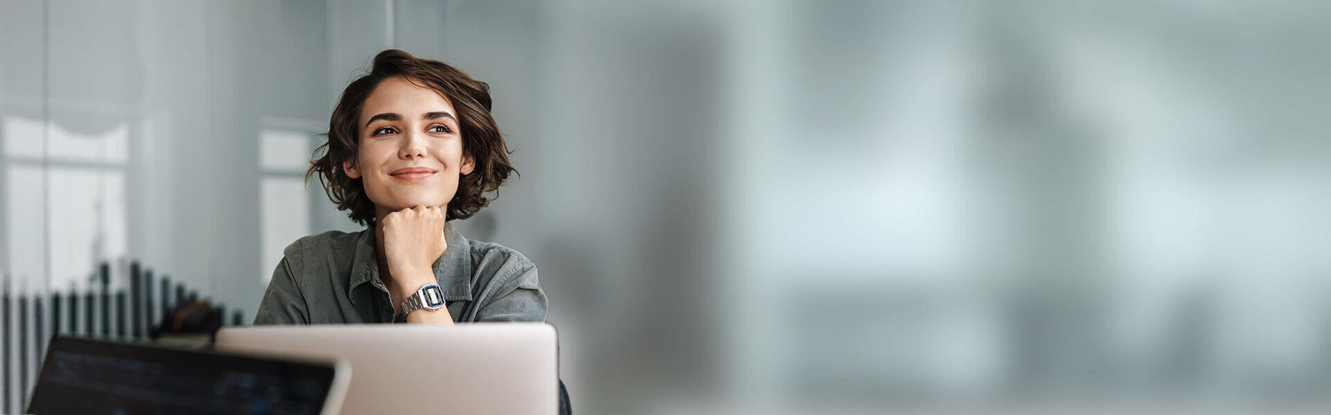 eine Frau sitzt lächelnd vor einem Laptop