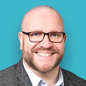 ein Mann mit Brille und einem Anzug lächelnd