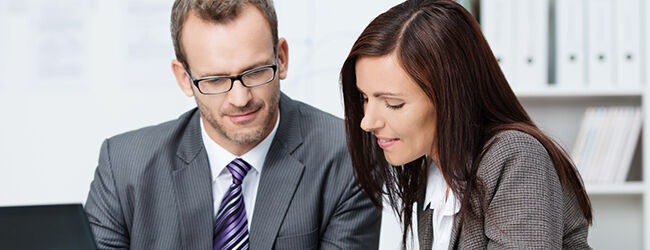 ein Mann und eine Frau, die auf einen Laptop schauen