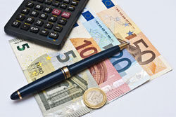 ein Taschenrechner und ein Stift auf einem Haufen Geld